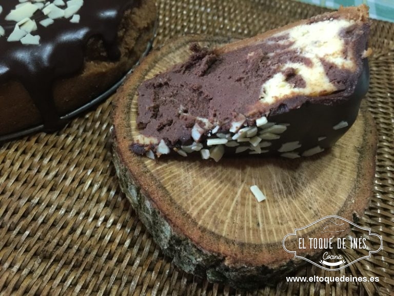 Después de transcurrir el tiempo de espera preparamos la cobertura, ponemos los ingredientes en un bol apto para el microondas o al baño maría y fundimos todo; removemos bien para que nos quede una mezcla suave.
Dejamos atemperar para que no esté muy líquida y se nos escape o nos estropee la superficie de nuestra tarta.
La echamos con cuidado por toda la superficie y decoramos si queremos con virutas de chocolate blanco, perlitas de chocolate, nueces picadas u otros frutos secos que nos guste,