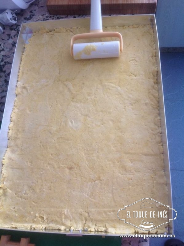 Y llega la hora del montaje...
Colocamos un papel de horno sobre la fuente que vamos a usar, echamos la mitad de la masa y yo la estiro con ayuda de un rodillo pequeño.