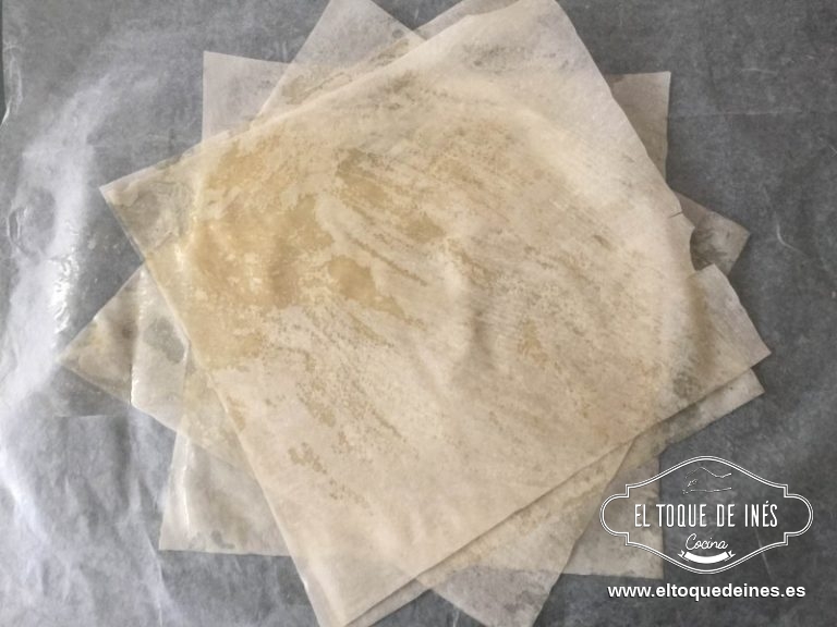 Cogemos uno de los cuadrados de pasta, pintamos un poco con mantequilla, le colocamos encima otro cuadrado, pero en distinta dirección, pintamos otro poquitín con mantequilla y encima otro cuadrado.