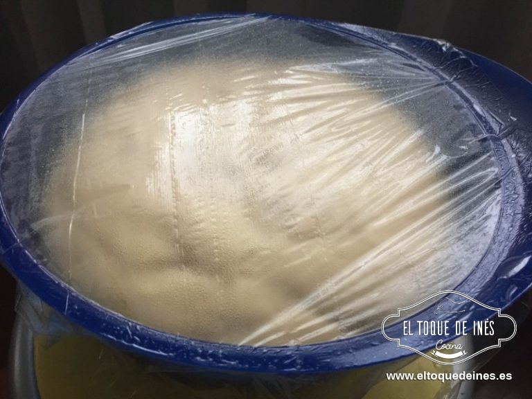 Ponemos la masa en un bol engrasado, tapamos con film transparente engrasado también para que no se pegue y dejamos reposar en sitio calentito entre una hora y media y dos horas para que suba la masa.