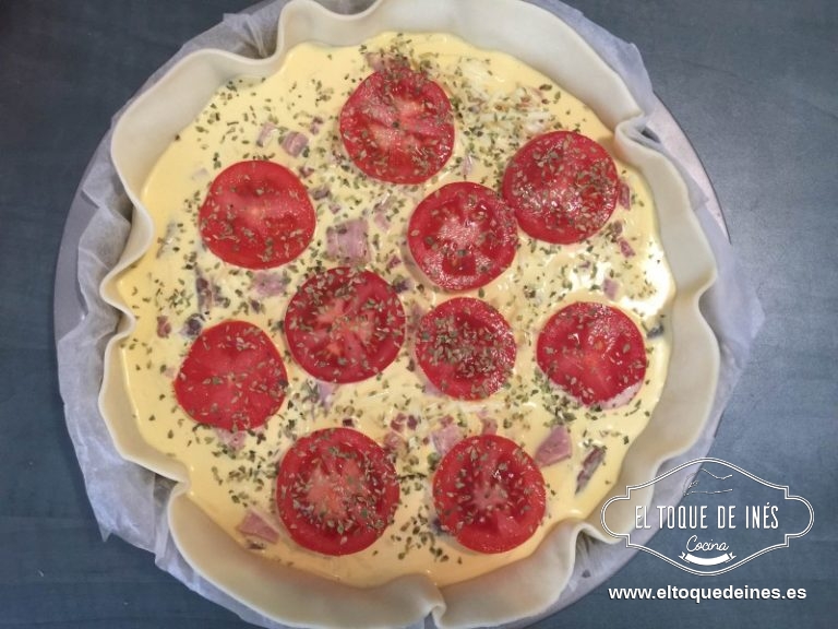 Vertemos la mezcla sobre la masa, colocamos encima las rodajas de tomate y espolvoreáis con el orégano.
