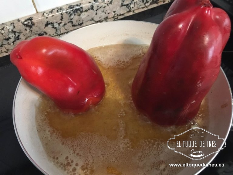 Para que no se salga el contenido de los pimientos ponemos una espátula sobre el agujero y en vertical los ponemos sobre el aceite bien caliente para que se selle la entrada.