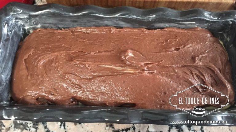 Vertemos sobre el molde la mitad o algo más de la mezcla; al resto le añadimos el cacao en polvo y mezclamos con ayuda de una espátula; una vez que esté homogéneo lo echamos encima de la mezcla anterior; si queréis podéis con un tenedor o cuchara mezclar ambas partes, yo la dejo así tal cual porque el cacao por su propio peso va a bajar y ya se mezclan.