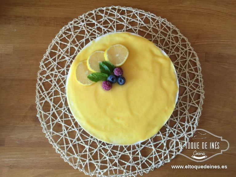 Pasadas las horas vertemos con ayuda de una cuchara o una espátula el lemon curd (os pongo la receta en notas) por encima, la cantidad dependerá del grosor de la capa que queráis dejarle, colocáis unas rodajas de limón, unas hojas de menta o unos frutos rojos, eso a vuestro gusto.