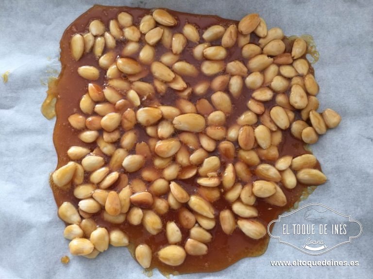 En una sartén echamos el azúcar y dejamos que vaya cogiendo un color dorado, cuando llegue ese momento añadimos las almendras y dejamos que se caramelicen un poco; retiramos sobre un papel de hornear y dejamos que se enfríen.
