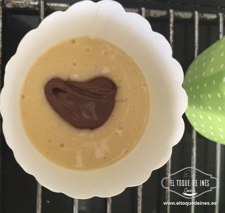 Llenamos 1/3 de la capacidad de los moldes, encima una cucharadita de la crema de cacao, cubrimos con otro poco de mezcla, no hasta arriba de todo, sino saldrán de los moldes.