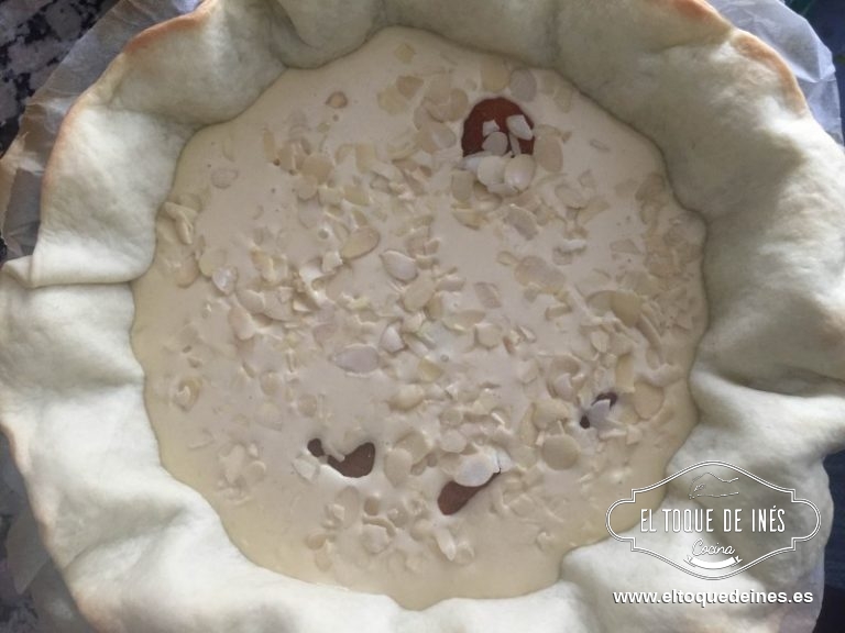 Echamos la mezcla en la masa, repartimos los orejones por la superficie, se irán hacia el fondo por el peso y repartimos unas cuantas almendras laminadas por encima.