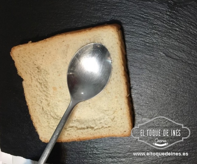 Aplastamos el interior de cada rebanada de pan de molde, sin tocar a los bordes; nos podemos ayudar de una cuchara.