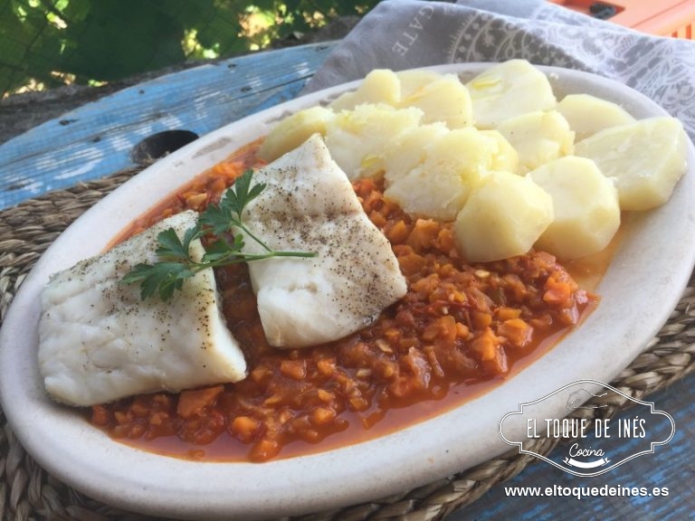 Servimos la merluza con las patatas y la salsa de tomate.