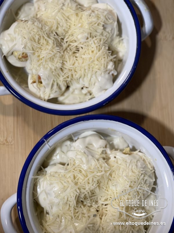 Terminamos de rellenar los huevos, repartimos la bechamel por encima y espolvoreamos con queso rallado al gusto.