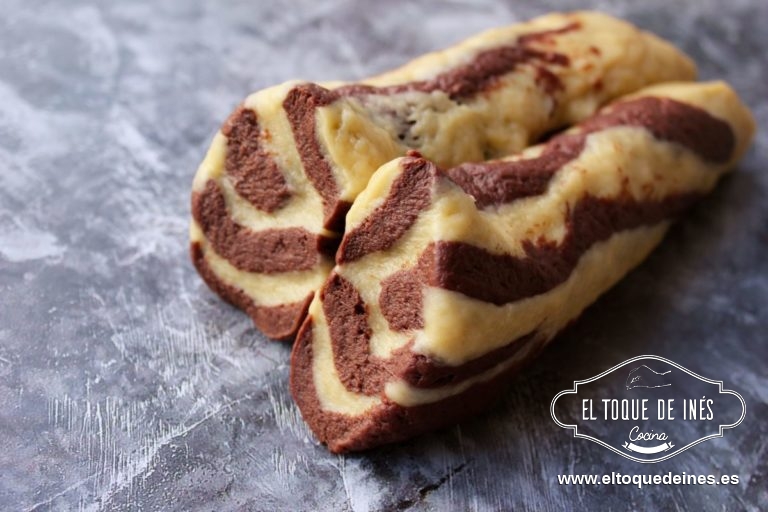 Formamos un rulo alargado, lo cortamos por la mitad y, con un rodillo, estiramos una de las mitades hasta conseguir una plancha del grosor de una moneda.