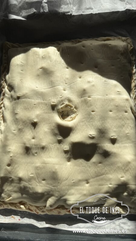 Cubre con otra lámina de hojaldre (o dobla la lámina sobre sí misma si es muy grande).
Cierra los bordes para sellar.
Pinta la superficie con huevo batido para un acabado dorado y brillante.
Haz pequeños cortes o agujeros con un tenedor en la parte superior para que salga el vapor.