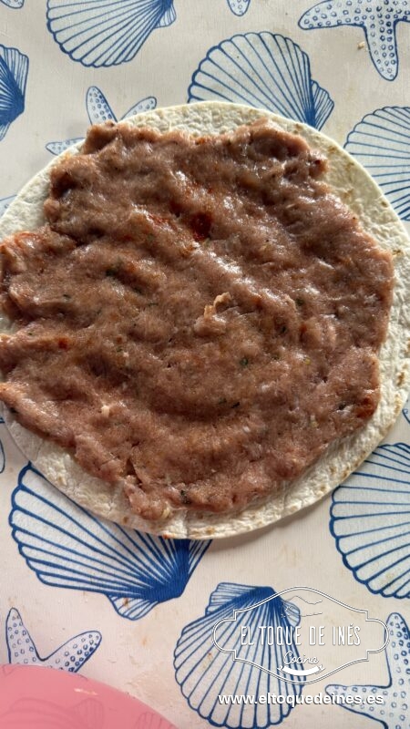 Colocamos una tortilla, pulverizamos un poco de aceite,y encima colocamos una bola de la mezcla de carne y la extendemos bien por toda la superficie.